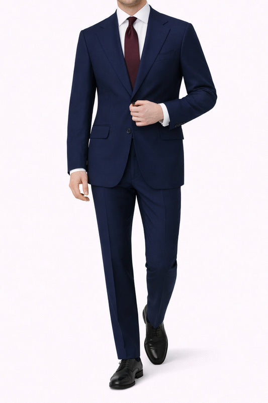 Man wearing a navy suit with a white shirt and maroon tie on a white background