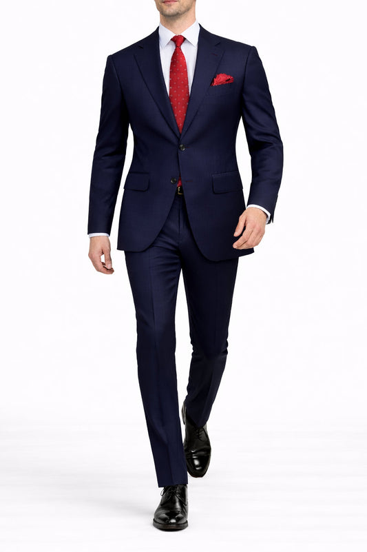 Man wearing a navy suit with a red tie and pocket square on a white background