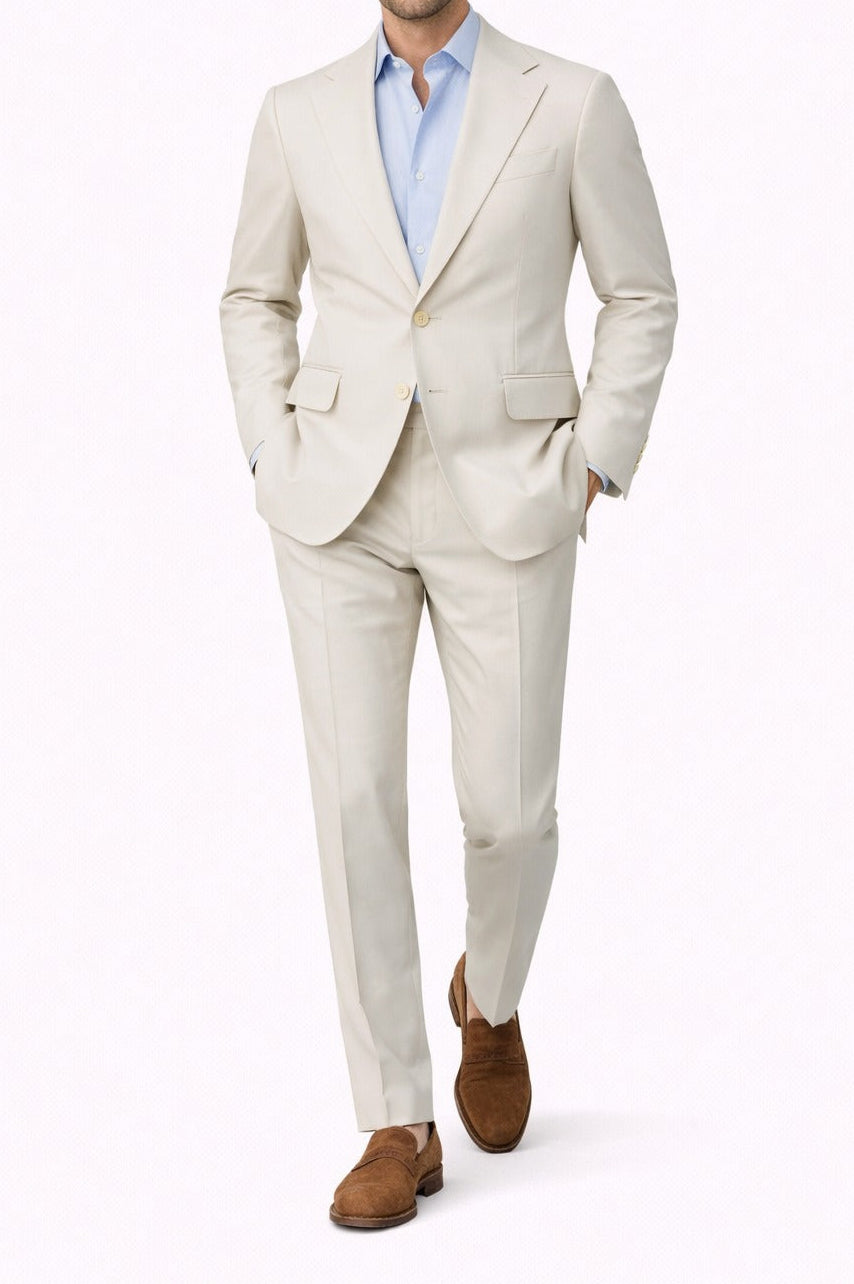 Man wearing a light beige suit with a blue shirt on a white background
