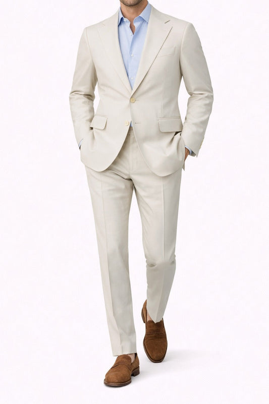 Man wearing a light beige suit with a blue shirt on a white background